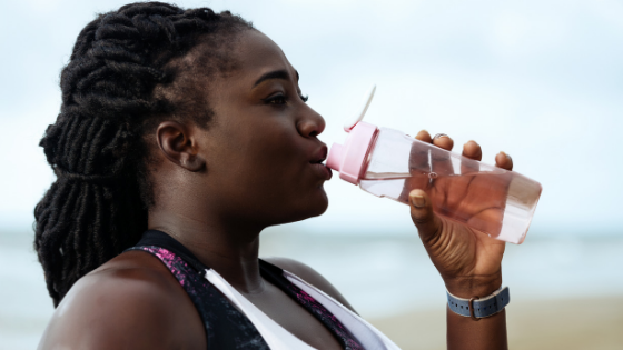 Woman drinking water from reusable water bottle.